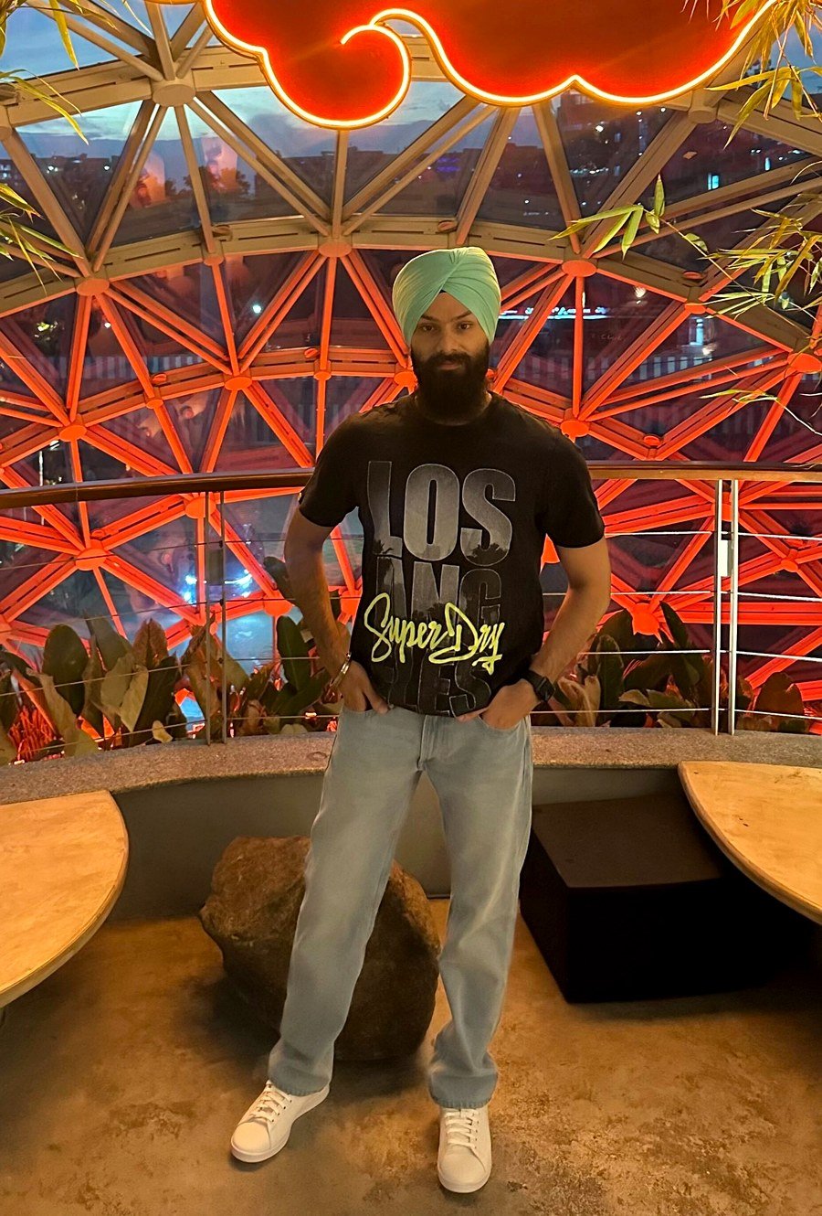 Harpreet Singh standing beneath a geodesic dome with neon signage, Bangalore